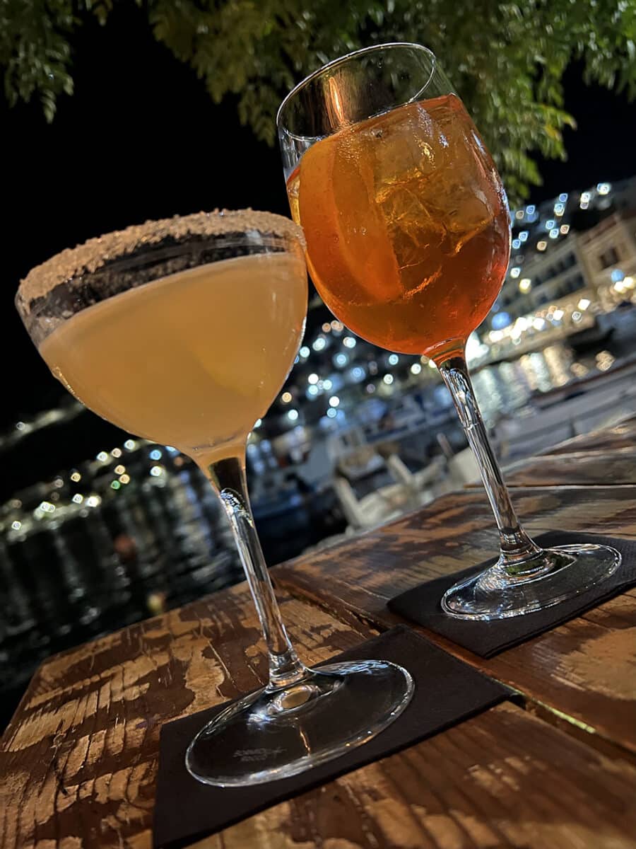 Drinking cocktails down by the harbour, night time in Symi, Greece.